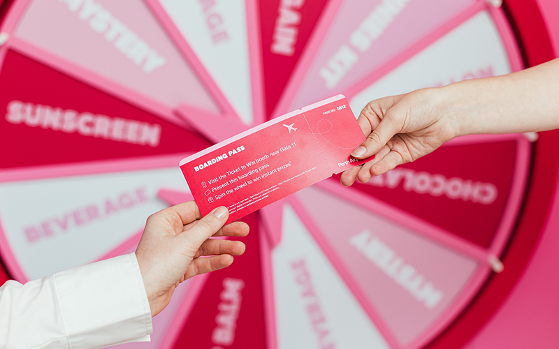 Hands passing pink Ticket to Win boarding pass