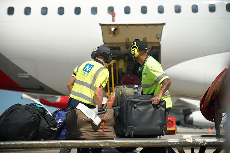 Two men loading baggage into a plane